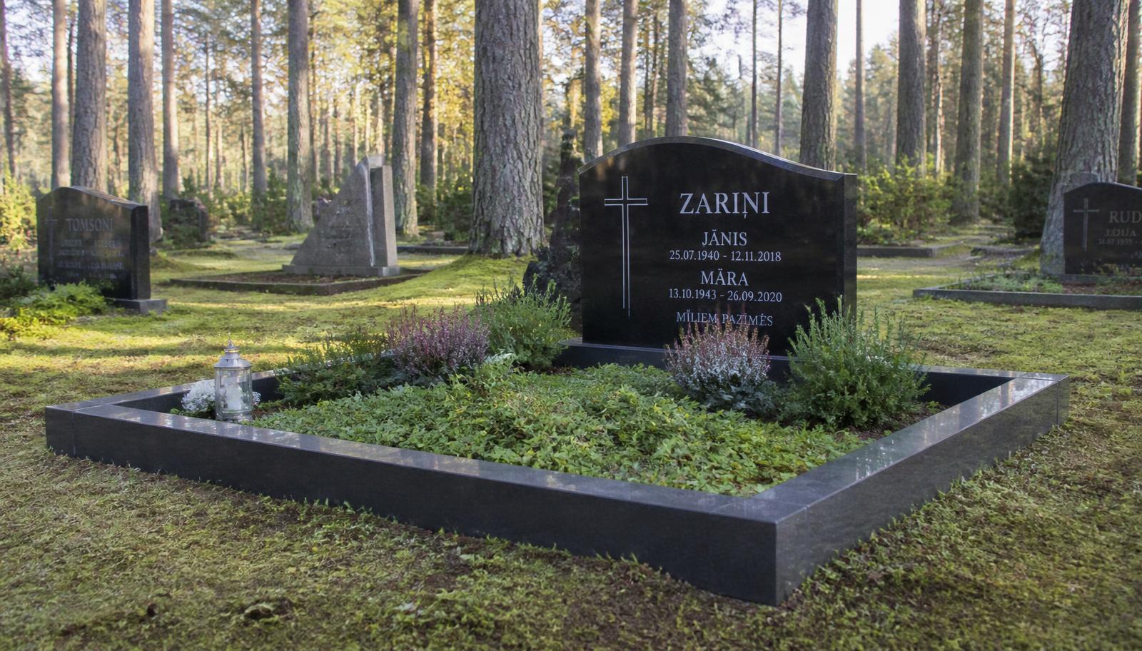 Melna granīta kapu piemineklis ar granīta kapu apmalēm labiekārtotā kapavietā